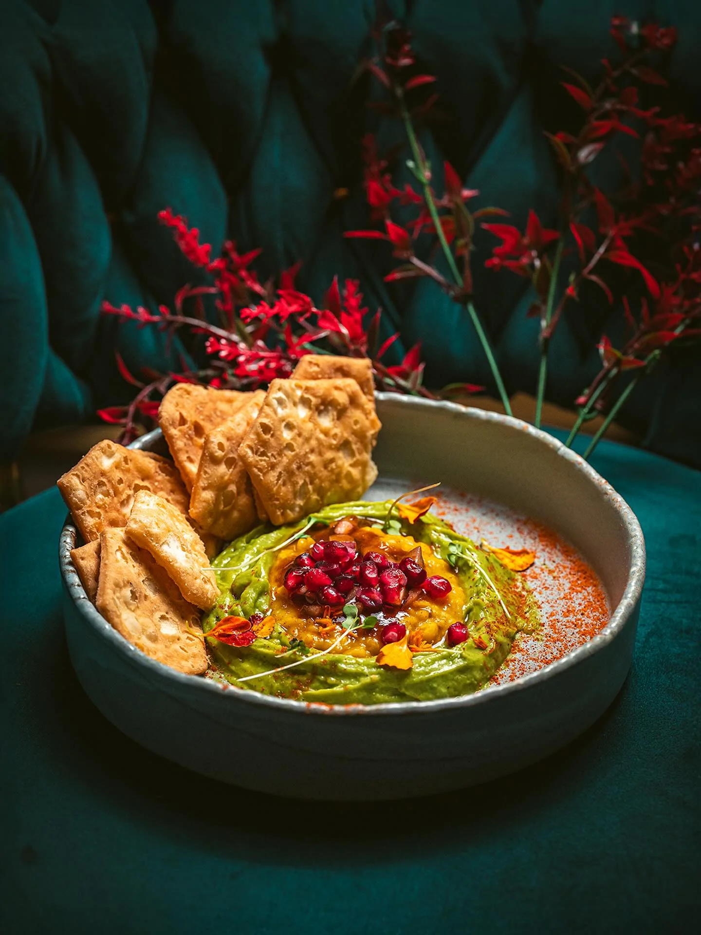 A colorful dip garnished with pomegranate and served with crisp bread
