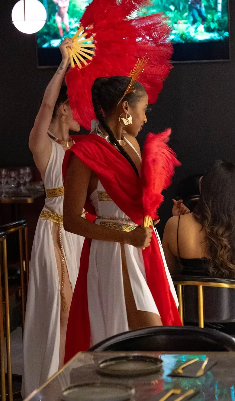 Performers with red feather fans entertaining guests at Befikre